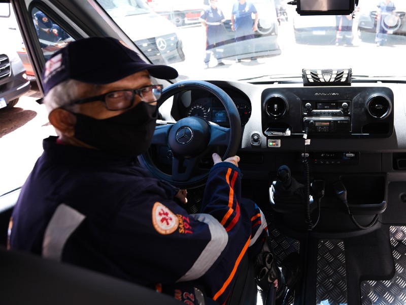 Na foto, o condutor José Carlos, o China, está dentro de uma ambulância, usando um uniforme do SAMU e com as mãos no volante 